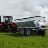 A Horwood Bagshaw Trailed Spreader being towed by a Case IH tractor in a lush green field