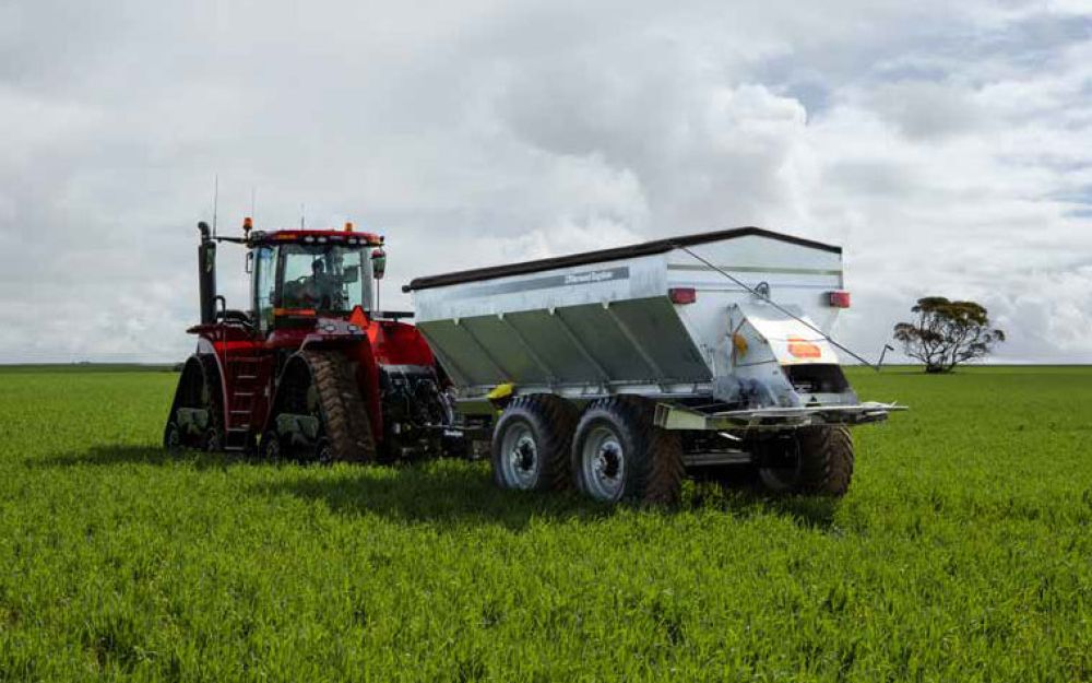 A Horwood Bagshaw Trailed Spreader being towed by a Case IH tractor in a lush green field