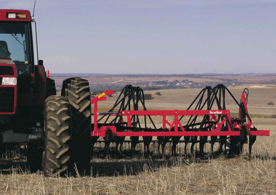 Horwood Bagshaw Scaribar being towed in a field of stubble by a red Case tractor