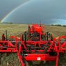 A Horwood Bagshaw Precision Seeding System in a field of stubble with a moody dark sky and rainbow in the distance